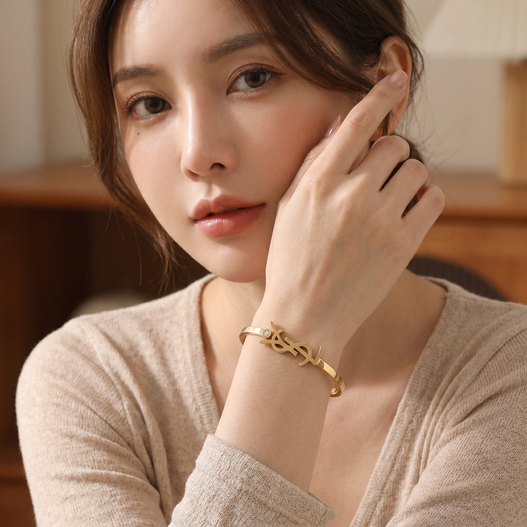 กำไลข้อมือสแตนเลสแท้ 316L สีทอง ดีไซน์จี้สัญลักษณ์โมโนแกรมตัวอักษรไขว้ประดับเพชร CZ พรีเมียมลักชูรี ไม่ลอกไม่ดำ [The Majestic Monogram Bangle]
